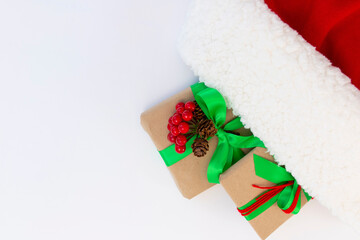 Gifts wrapped in craft paper and decorated with green and red ribbons flat lay on white background.