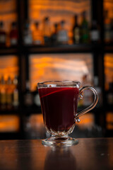 A young smiling bartender in a black apron prepares mulled wine
