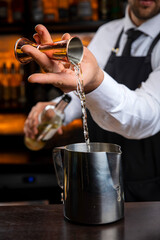 A young smiling bartender in a black apron prepares mulled wine
