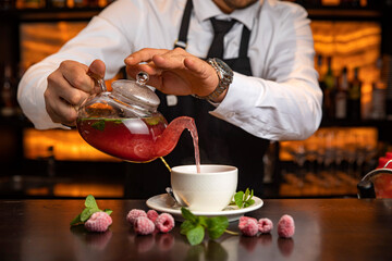 A male bartender pours hot tea at the bar in a restaurant
