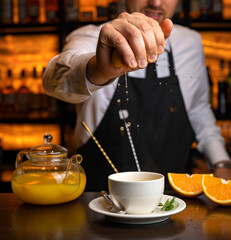 A male bartender pours hot tea at the bar in a restaurant
