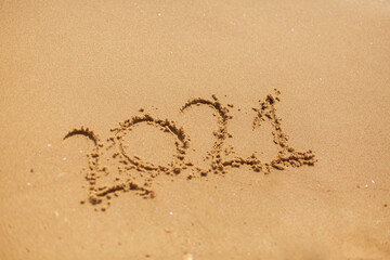 2021 hand written sign on sandy beach. Happy New year 2021