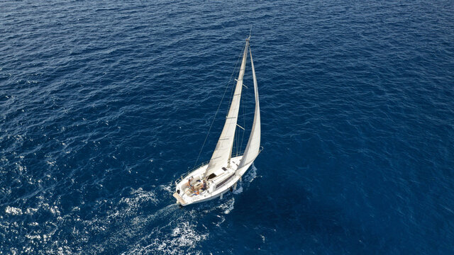 Aerial drone photo of small sailboat cruising deep blue Ionian sea