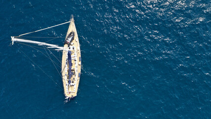 Aerial drone photo of beautiful sailboat anchored in Aegean deep blue sea
