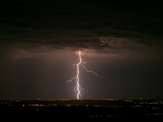 Eerie scenery of lightning strike hitting a town in a dark night