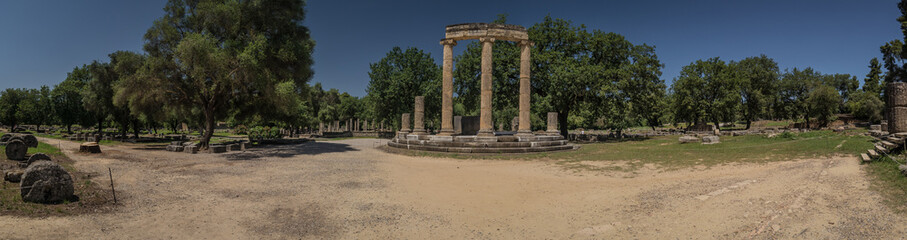 Fototapeta na wymiar Vertical panorama of archeological ruins consisting of diffrent columns or pillars taken on a sunny day in the ancient site of Olympia, Greece