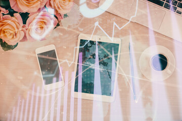 Double exposure of forex graph hologram over desktop with phone. Top view. Mobile trade platform concept.