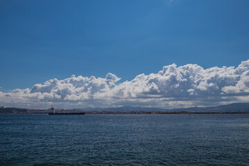 A big cargo ship or carrier traveling through the Dardanele strait in Turkey on a cloudy day, looking through a window of a ferry going towards Canakkale.
