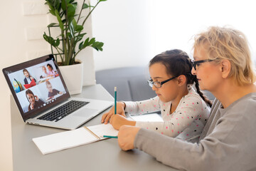 Helpful granny. Helpful loving granny assisting her cute granddaughter making homework