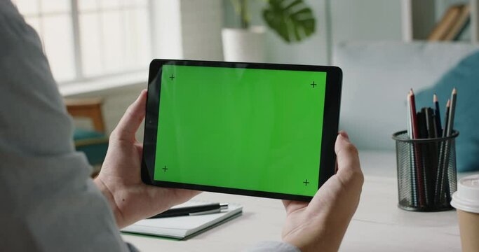 Close up shot of hands holding a tablet computer with green mock up screen. A template for video conference or online store 4k footage