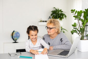 Helpful granny. Helpful loving granny assisting her cute granddaughter making homework