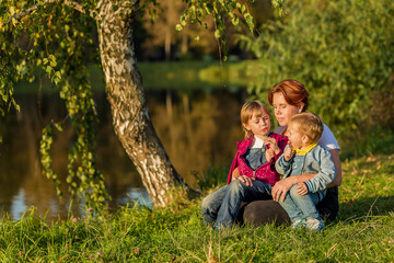 Fototapeta premium happy family Mom and children sit on the river bank