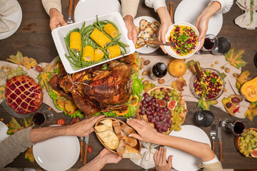 Overview of hands of four family members holding plates with festive food