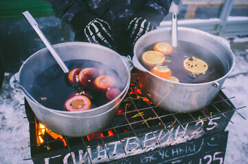 Spicy mulled wine in big red bowls on Christmas market, the text is in russian and means exactly...