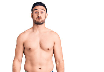 Fototapeta premium Young handsome man wearing swimwear puffing cheeks with funny face. mouth inflated with air, crazy expression.