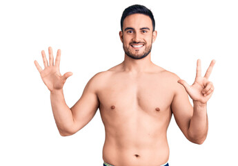 Young handsome man wearing swimwear showing and pointing up with fingers number eight while smiling confident and happy.