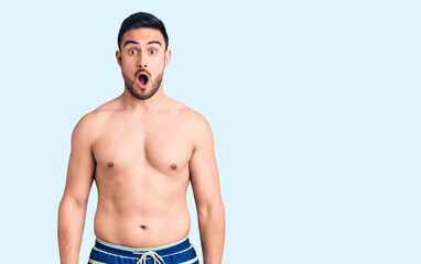 Fototapeta premium Young handsome man wearing swimwear afraid and shocked with surprise and amazed expression, fear and excited face.