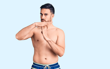 Fototapeta premium Young handsome man wearing swimwear doing time out gesture with hands, frustrated and serious face