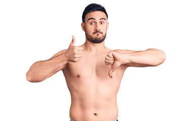 Fototapeta premium Young handsome man wearing swimwear doing thumbs up and down, disagreement and agreement expression. crazy conflict