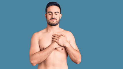 Young handsome man wearing swimwear smiling with hands on chest with closed eyes and grateful...