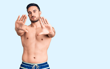Young handsome man wearing swimwear doing frame using hands palms and fingers, camera perspective