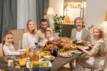 Contemporary family of three generations having dinner by served festive table