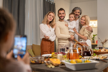 Contemporary affectionate three generation family posing by festive table