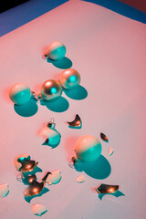 Broken christmas ball on a colored board with colored contrasty illumination, concept.