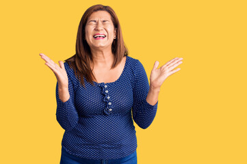 Middle age latin woman wearing casual clothes celebrating mad and crazy for success with arms...