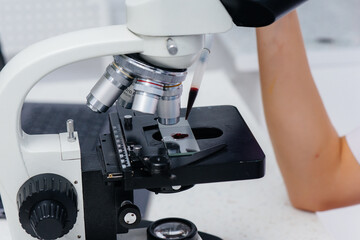 An infectious disease doctor works at a close-up microscope. Study of viruses and bacteria in the medical laboratory