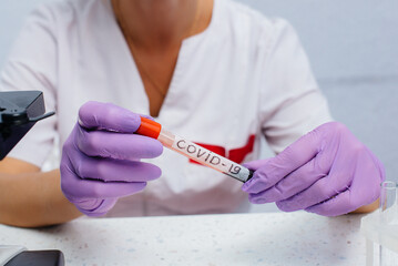 A female doctor in the laboratory holds a medical test tube with a positive test for COVID-19. Research of dangerous viruses and bacteria