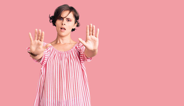 Beautiful young woman with short hair wearing casual summer clothes doing stop gesture with hands palms, angry and frustration expression