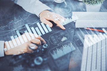 Double exposure of man's hands holding and using a phone and financial graph drawing. Analysis concept.