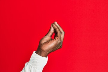 Fototapeta premium Arm and hand of african american black young man over red isolated background doing italian gesture with fingers together, communication gesture movement