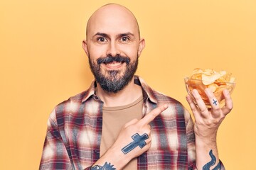 Young handsome man holding potato chip smiling happy pointing with hand and finger