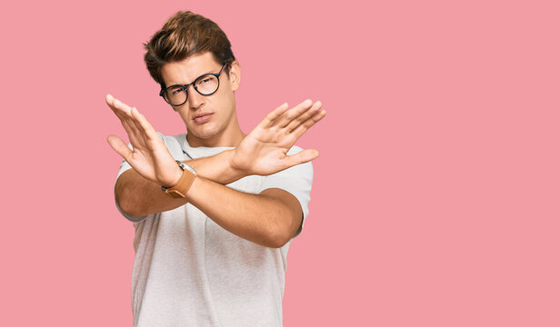 Handsome caucasian man wearing casual clothes and glasses rejection expression crossing arms doing negative sign, angry face