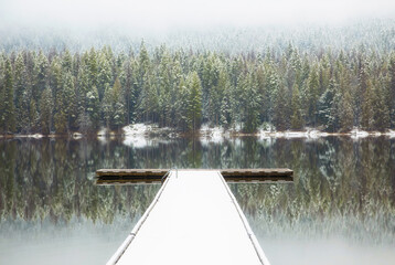 Original winter landscape photograph of a snow covered dock on a still lake reflecting fir trees...
