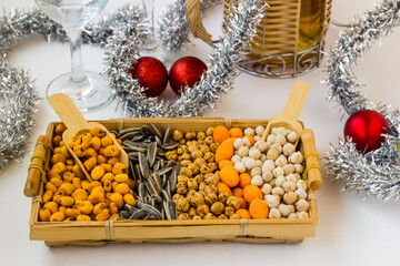 Mixed nuts wicker basket on white surface with wine bottle and christmas ornaments
