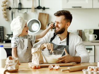 Cheerful dad and kid having fun while cooking together.