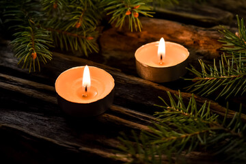 Obraz na płótnie Canvas Two burning candles, fir branches on an old, wooden background. Composition for new year and christmas.