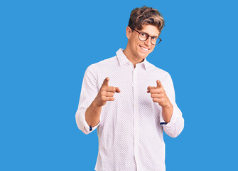 Young handsome man wearing business clothes and glasses pointing fingers to camera with happy and funny face. good energy and vibes.