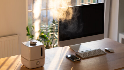 Close up of aroma oil diffuser on the table at home, steam from the air humidifier. Ultrasonic technology, increase in air humidity indoors, comfortable living conditions. 