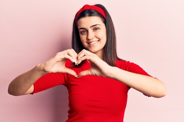 Young beautiful girl wearing casual t shirt and diadem smiling in love doing heart symbol shape with hands. romantic concept.