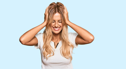 Fototapeta premium Beautiful blonde young woman wearing casual white tshirt suffering from headache desperate and stressed because pain and migraine. hands on head.