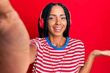 Beautiful hispanic woman taking a selfie photo wearing headphones celebrating victory with happy smile and winner expression with raised hands