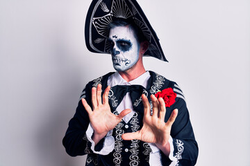 Young man wearing mexican day of the dead costume over white disgusted expression, displeased and...