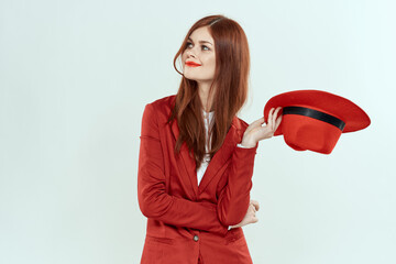 Elegant woman in red jacket hat holding long hair cropped light background