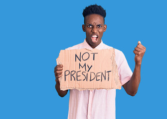 Young african american man holding not my president protest banner annoyed and frustrated shouting...
