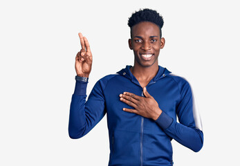 Young african american man wearing sportswear smiling swearing with hand on chest and fingers up,...