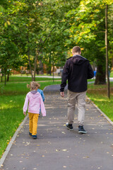 Fototapeta premium .Dad with children walking along the path in the park on an autumn walk.